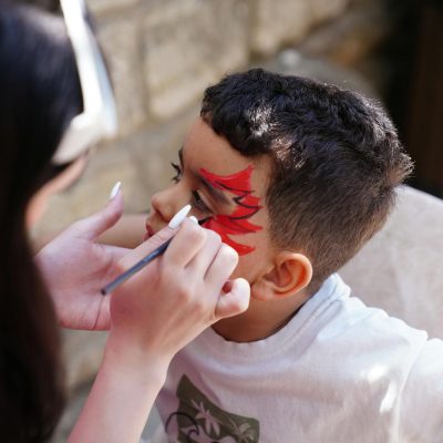 A child having their face painted with a vibrant design outdoors in Baku, Azerbaijan.